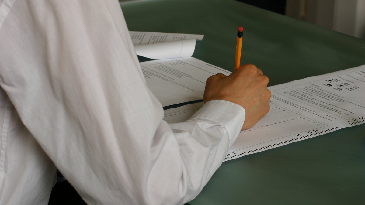 SAT 콜론 문제 풀이 — 답안지에 연필로 표시하는 손